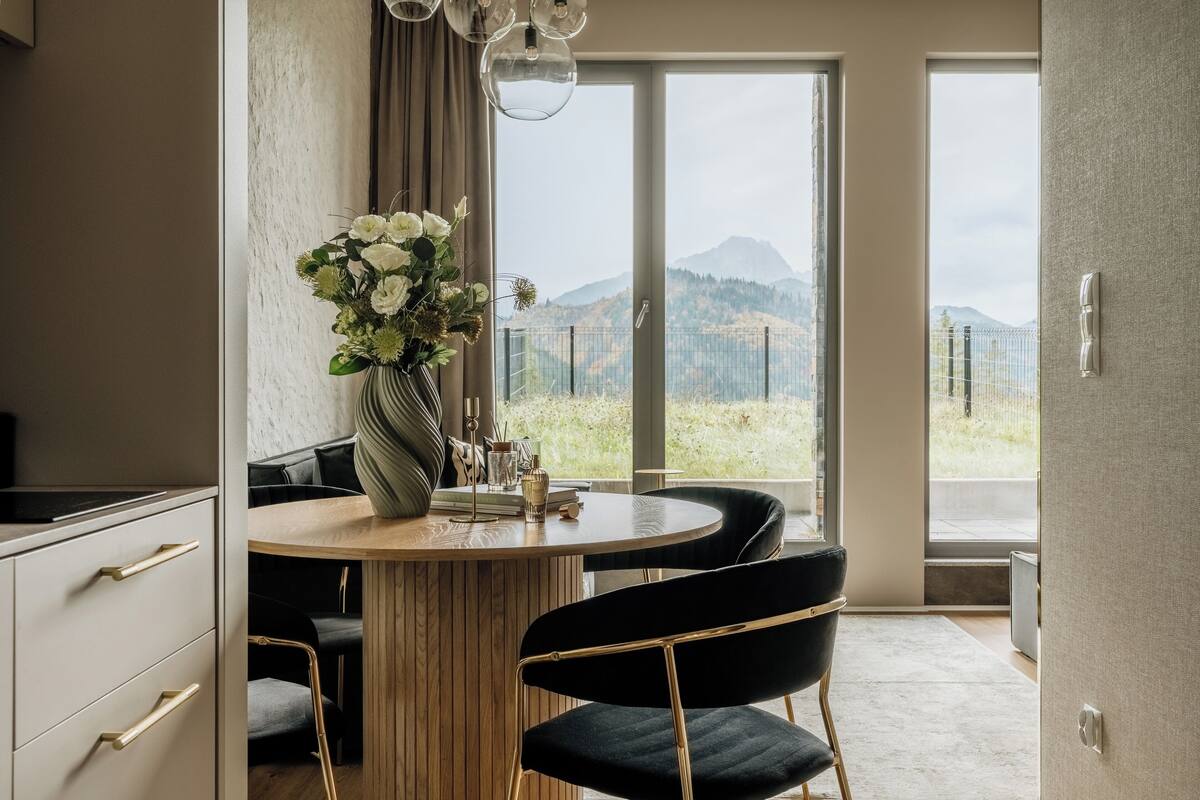 Una cocina moderna con comedor, ventanas amplias y vistas a las montañas.