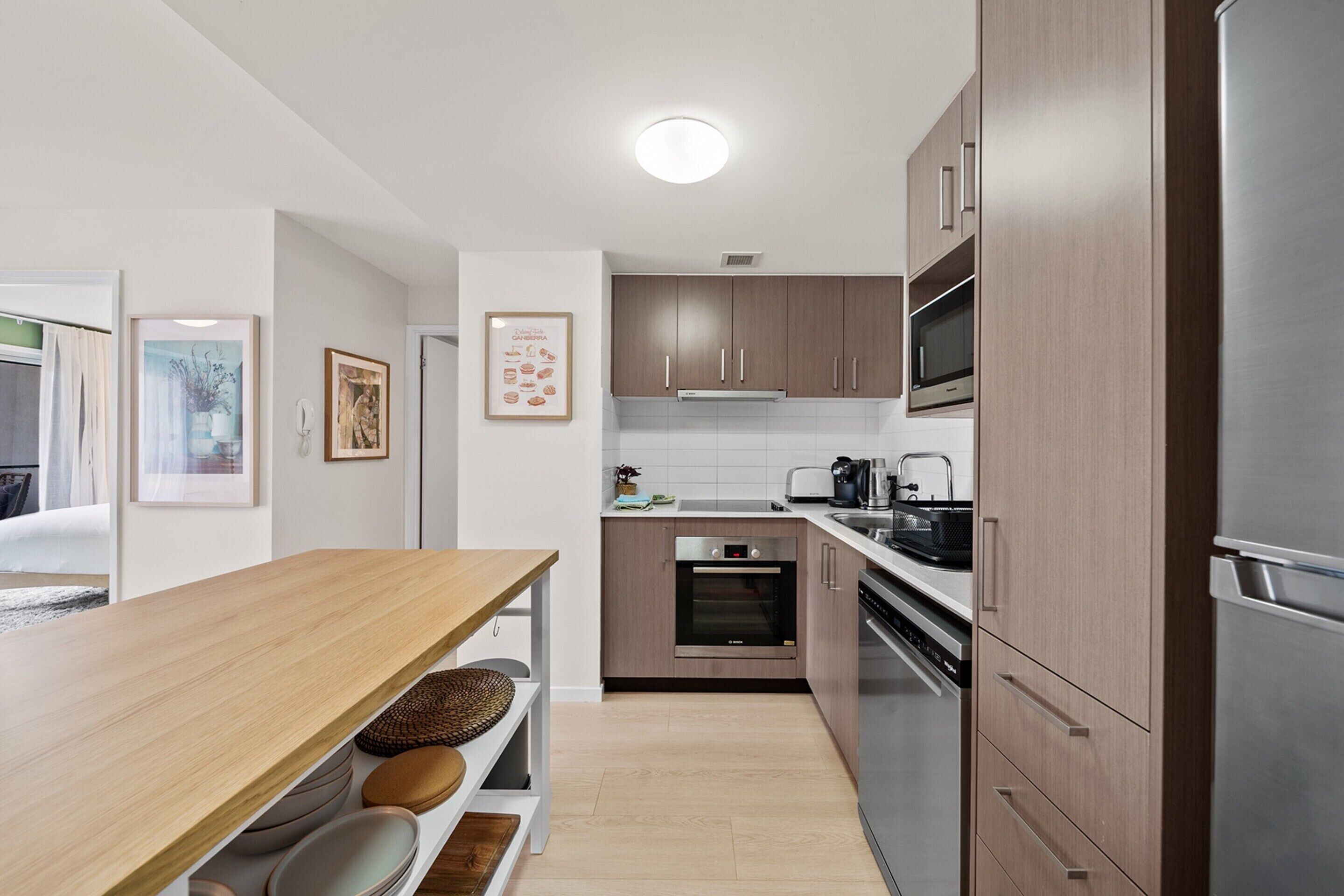Une cuisine moderne avec des meubles en bois, des appareils électroménagers en acier inoxydable et une table à manger en bois.