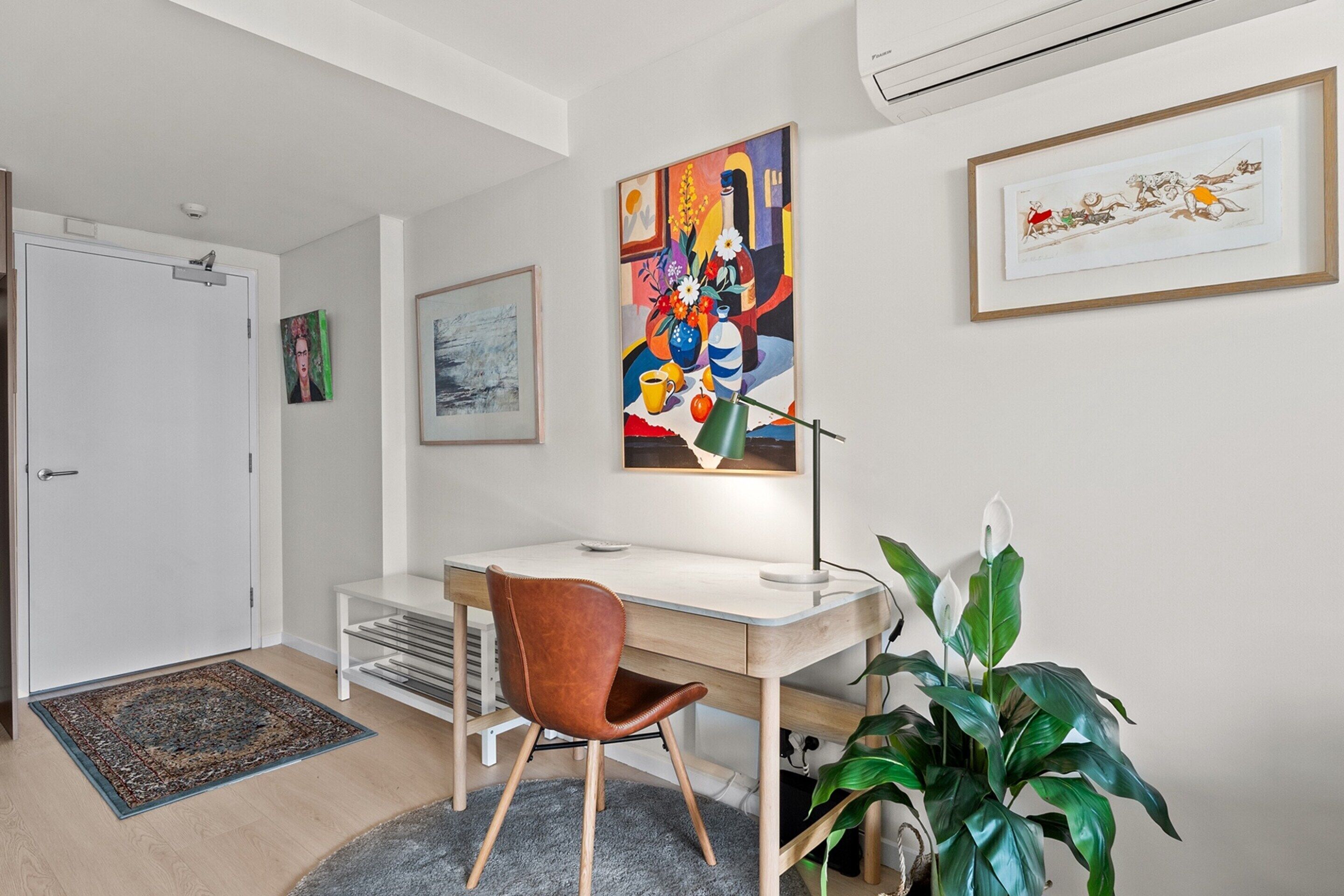 A modern office space with a desk, chair, and two framed artworks on the wall.