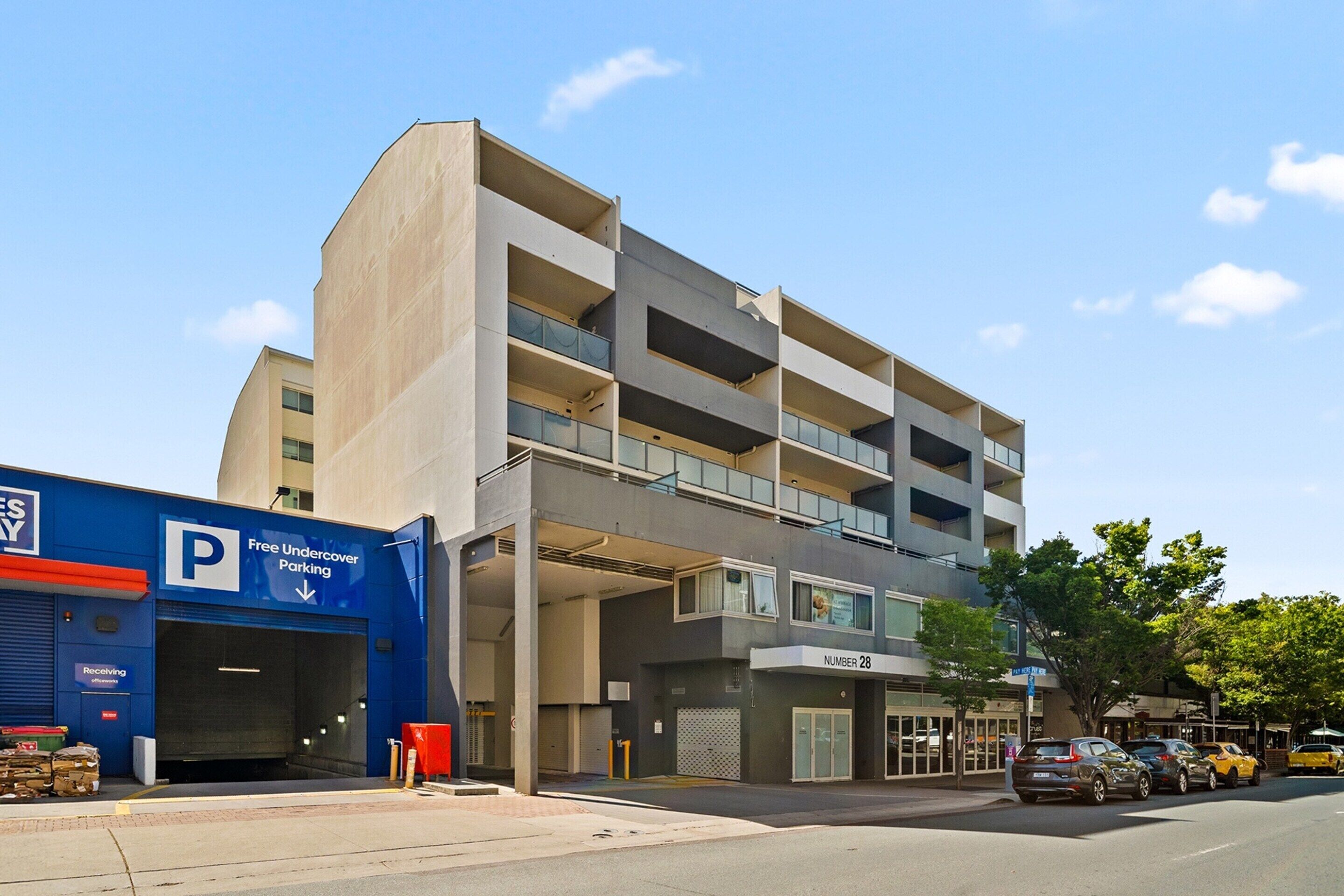 Un edificio de varios pisos con un estacionamiento subterráneo que indica "Estacionamiento Cubierto Gratis" y un local comercial con un letrero "NÚMERO 28".