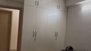 Ett sovrum med en takfläkt, en garderob och en säng med ett täcke.
