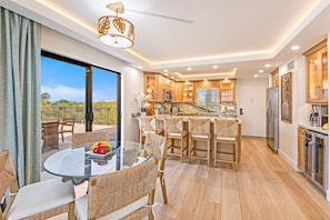 Una cocina moderna con comedor de cristal, armarios de madera y vistas al exterior.