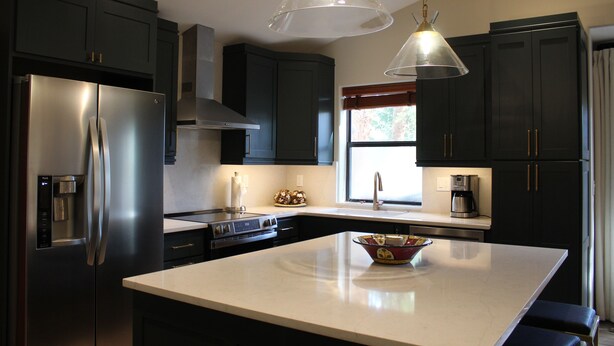 A modern kitchen with dark cabinets, stainless steel appliances, a central island, and pendant lighting. - Beautifully Remodeled Townhome on Peak 8 (Breckenridge)