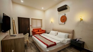 A bedroom with a bed, a desk, a chair, a TV, a wall-mounted air conditioner, and two wall sconces. - Friends Hotel Jordan (Amman)