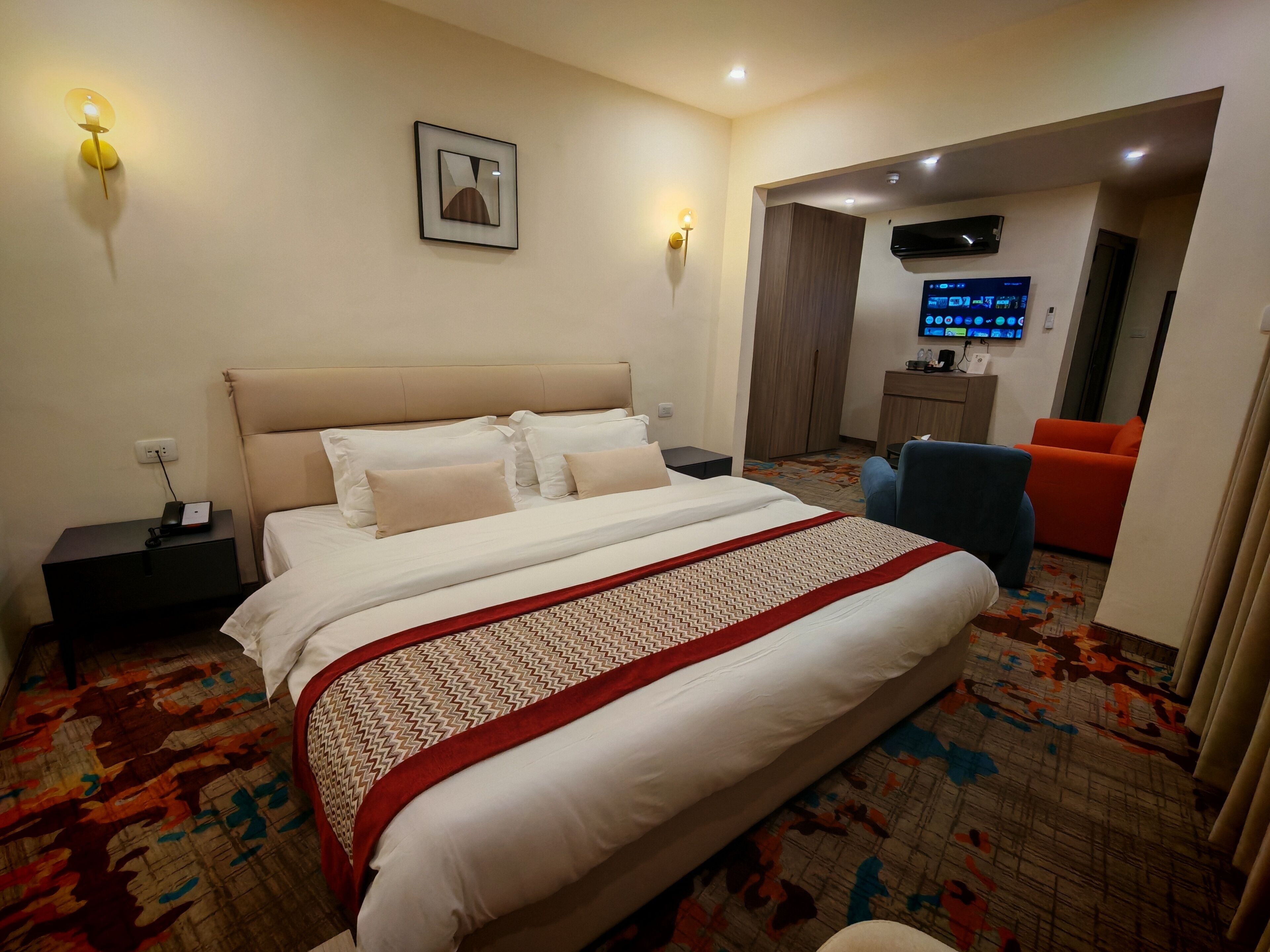 Una habitación de hotel con cama, mesitas de noche, televisor y sofá.