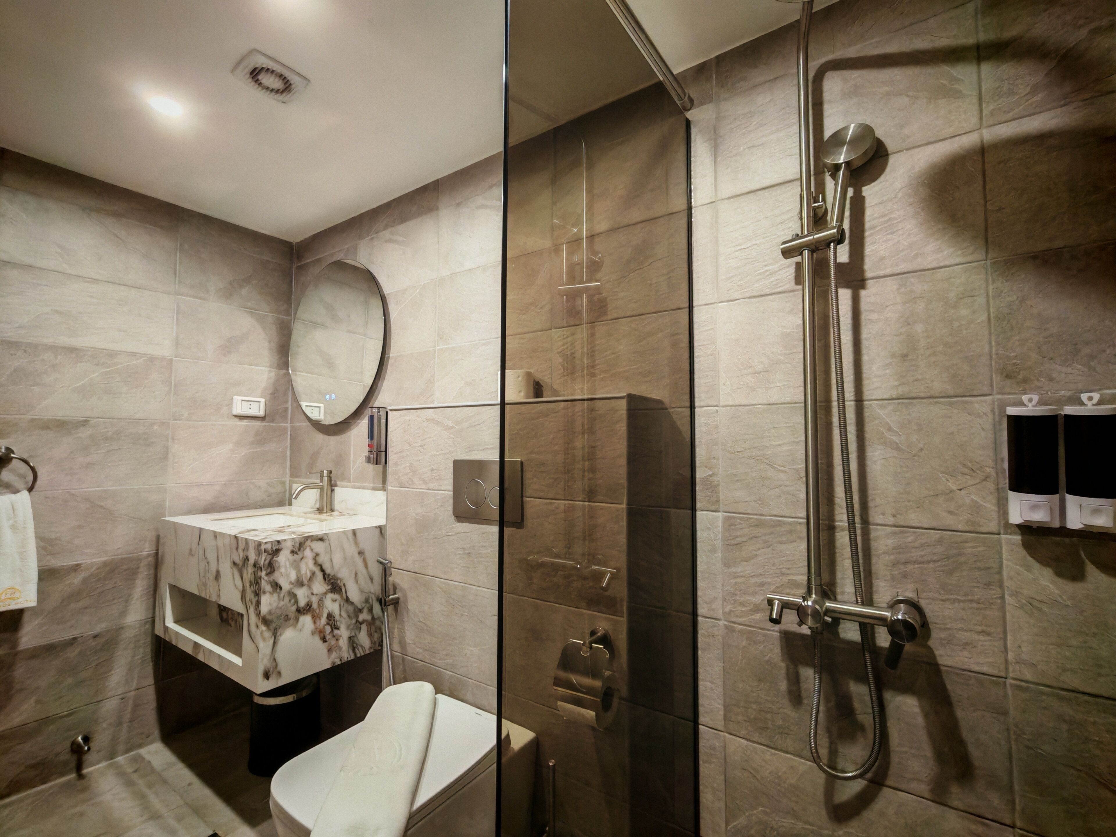 Un bagno moderno con cabina doccia in vetro, lavabo in marmo e toilette.