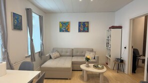 Ett modernt vardagsrum med en soffa, ett soffbord och två tavlor på väggen.