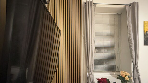 A bathroom with a wooden slat wall, a window with blinds, and a vase with flowers on the windowsill. - Apartment in the heart of Esbjerg Center (Esbjerg)