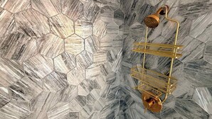 Une salle de bain avec un carrelage à motifs hexagonaux et une douche dorée.