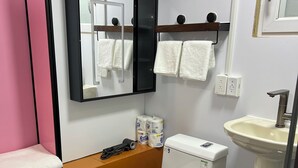 A compact bathroom with a white toilet, a sink, and a mirror above the mirror. - Seafront Studio C4 (Simpson Bay)