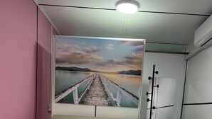 A hotel room with a bed, a large wall mural of a pier, and a ceiling light. - Seafront Studio C4 (Simpson Bay)