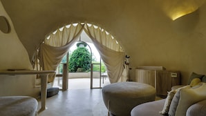 Una habitación acogedora y bien iluminada, con un amplio ventanal de arco, una mesita pequeña y asientos cómodos.