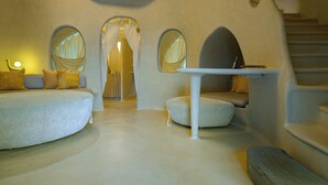 Un interior moderno con un diseño arquitectónico único, que incluye una zona de estar central, una mesita y una escalera.