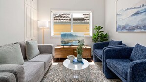 A living room with a sofa, a coffee table, a lamp, and a painting on the wall. - Bright 3-bed Apartment Near Coogee Beach (Sydney)