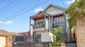 A two-story house with a balcony, a garage, and a stone wall. - Bright 3-bed Apartment Near Coogee Beach (Sydney)