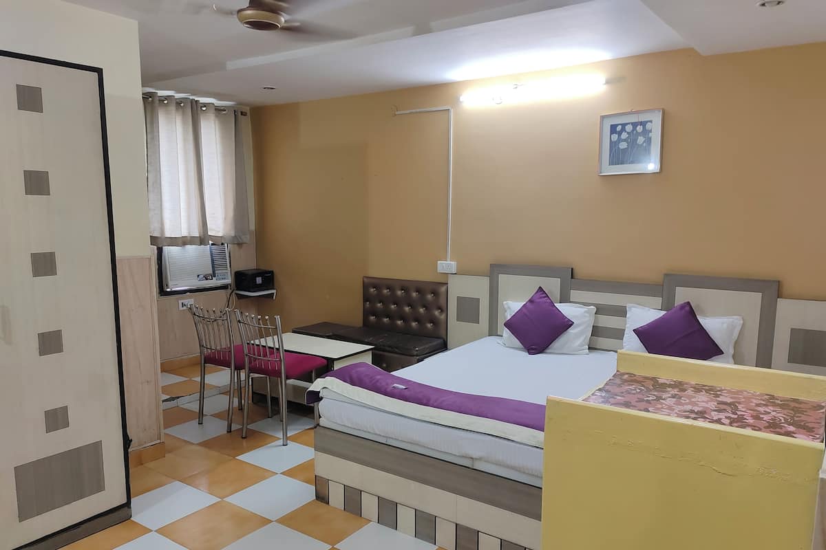 Una habitación de hotel con cama, mesita de noche, silla y escritorio con otra silla.