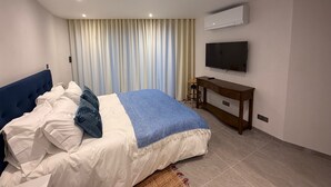 A modern hotel room with a bed, a TV, and a desk.