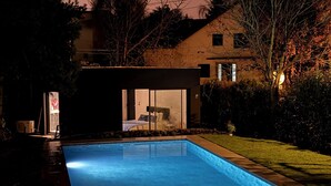 A modern house with a swimming pool, a visible bedroom, and a well-maintained lawn.