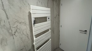 A bathroom with a white towel rack, a white door, and marble walls.