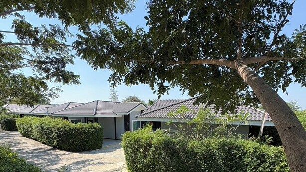 A modern building with a tiled roof, surrounded by well-maintained hedges and trees.