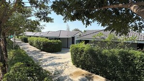 A pathway leading to a row of modern buildings with a tiled roof, surrounded by well-maintained hedges and trees.