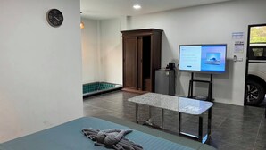 A hotel room with a bed, a desk, a television, and a small refrigerator.