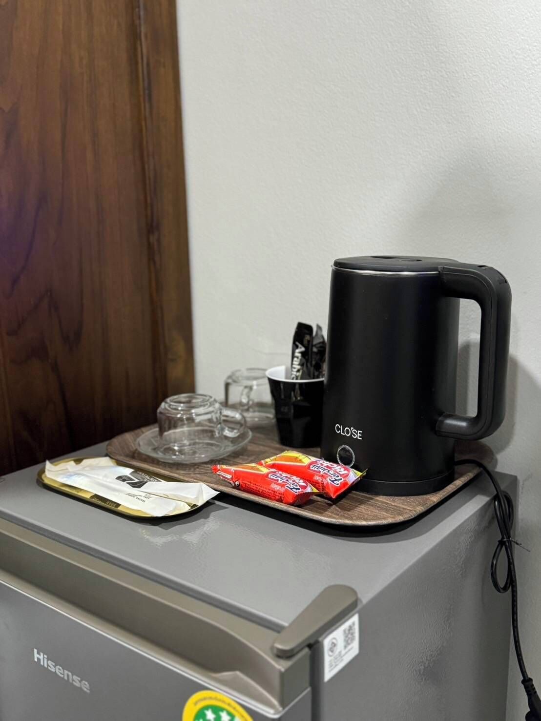 Una cafetera petita sobre una taula amb un plat, un paquet d'aperitius i un got.