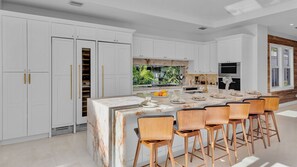 A modern kitchen with white cabinetry, a marble island, and a dining area with wooden chairs. - **VOGUE VILLA @ OLD TOWN** Home & Pool + Last Key White Glove Service... (Key West)