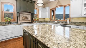 A spacious kitchen with granite countertops, white cabinetry, and a large island. - Boulder Cove Lakefront Estate (Big Bear Lake)
