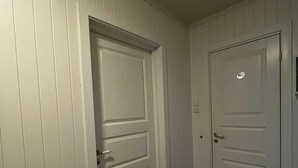 Een hal met twee witte deuren, waarvan één met een ‘WC’ bordje is aangegeven, en houten vloeren.