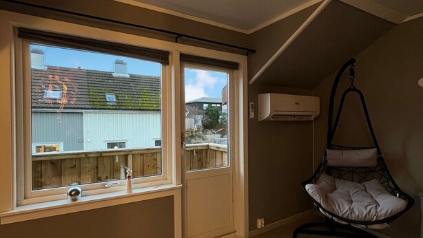 Een kamer met een groot raam, een hangstoel en een airconditioner.
