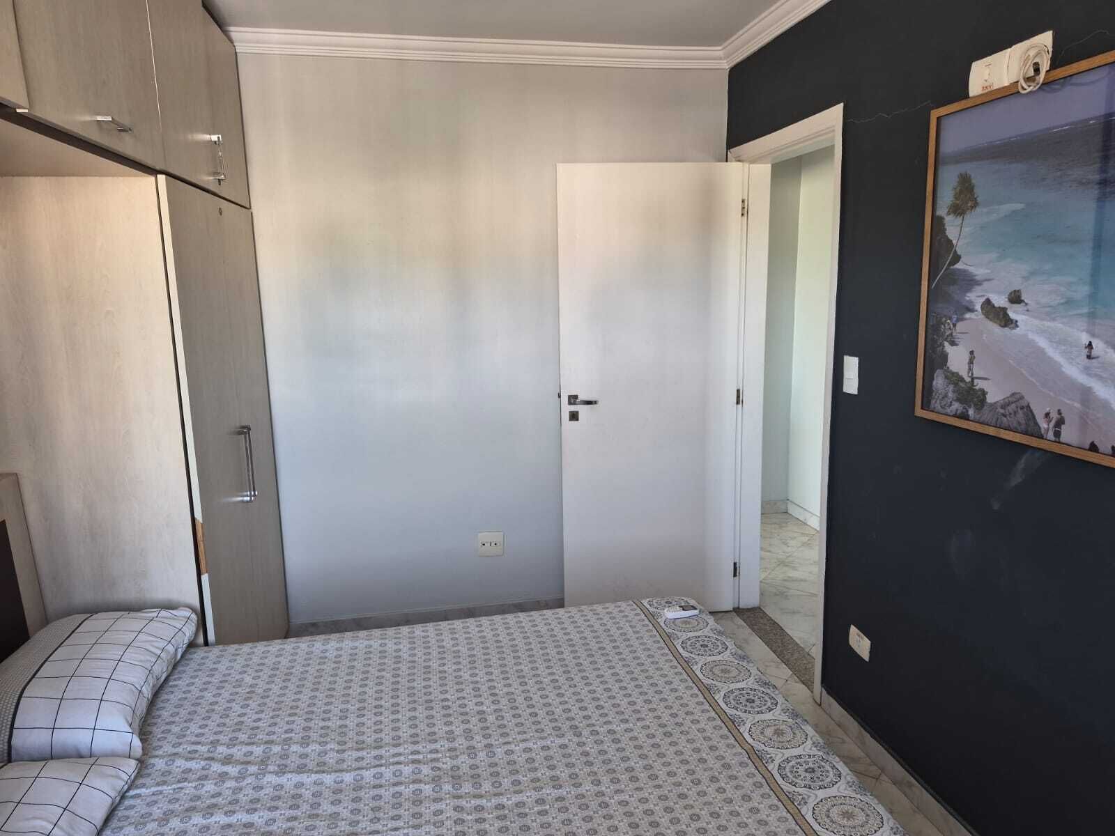 Ein Schlafzimmer mit einem Bett, einem Kleiderschrank, einer Tür und einem gerahmten Bild an der Wand.