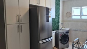 Eine Küche mit Edelstahlkühlschrank, Waschmaschine und Schränken.