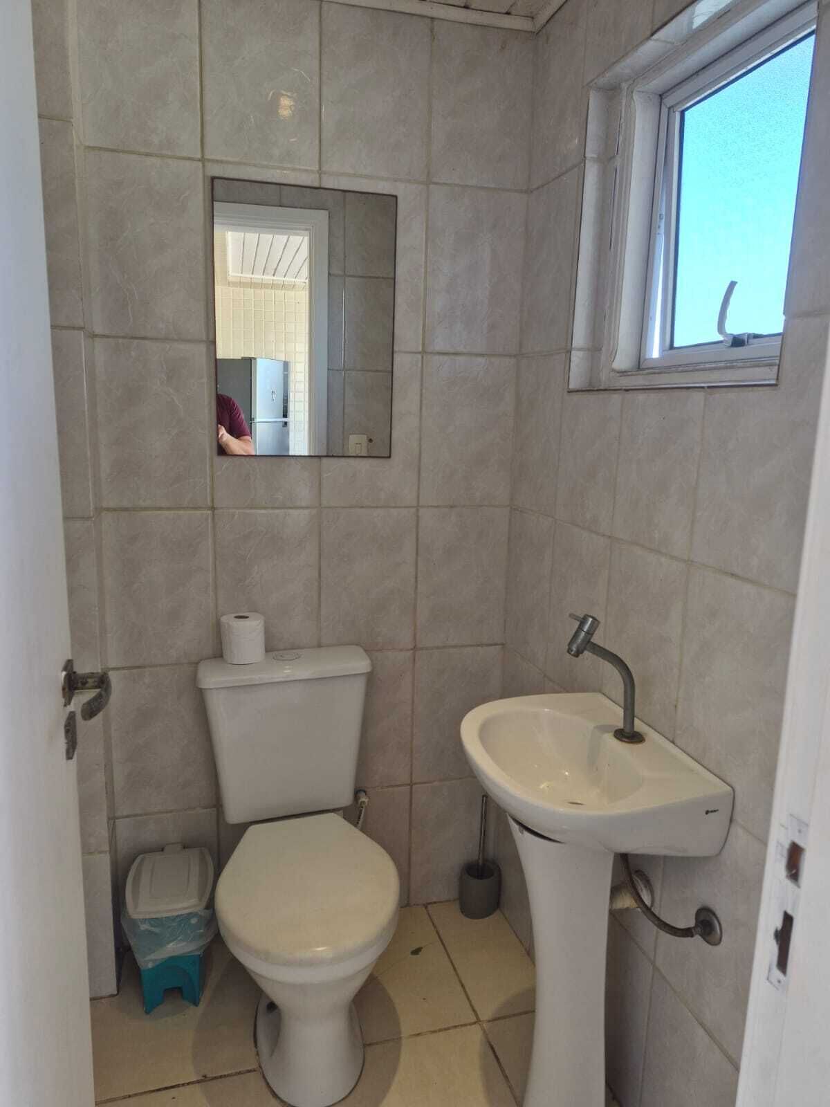 A bathroom with a toilet, sink, and mirror.
