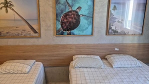 Ein Hotelzimmer mit zwei Betten, einem Holzkopfstück und drei gerahmten Bildern an der Wand.
