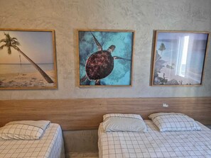 Habitación de hotel con dos camas, cabecero de madera y tres cuadros en la pared.