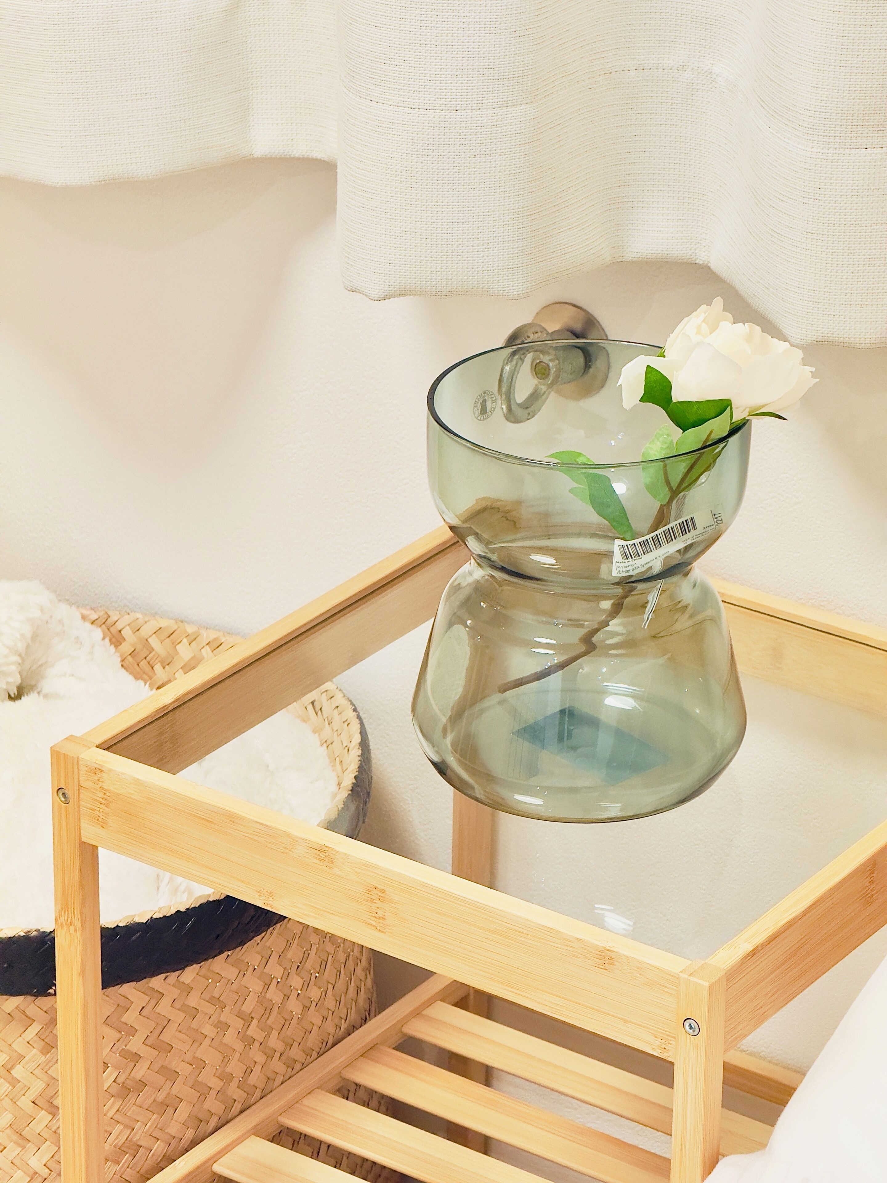Un florero de vidrio transparente con una flor blanca sobre una mesa de madera.