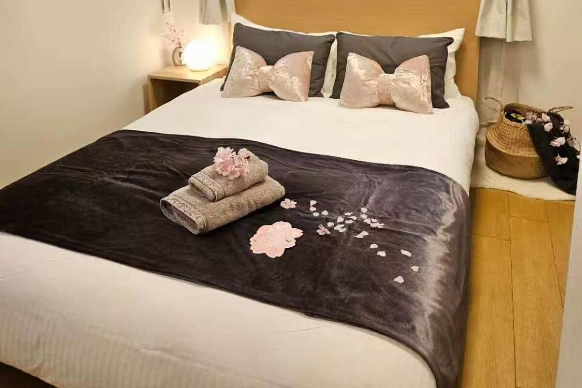 Una cama bien hecha con un edredón marrón oscuro, varias almohadas y un objeto decorativo sobre la cama.