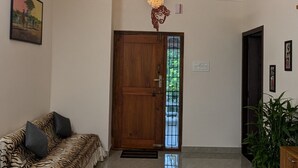 Un vestíbulo amplio con ventilador de techo, araña, puerta de madera, sofá con estampado de tigre y una planta en maceta.