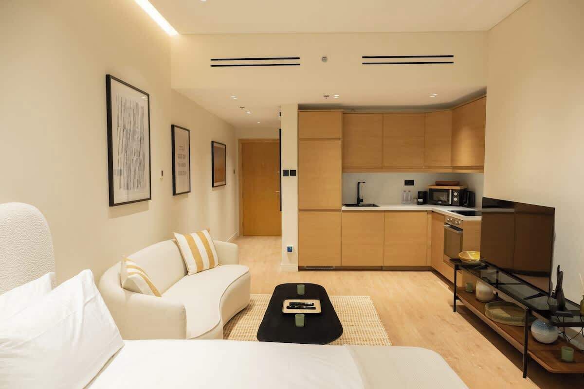 Un espace de vie moderne et compact comprenant un coin cuisine, un canapé, une table basse et un lit.