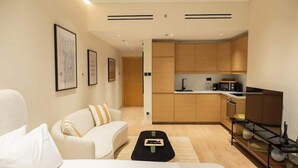 A modern, compact living space with a kitchenette, a sofa, a coffee table, and a bed. - Stylish cozy studio in the heart of Business Bay (Dubai)