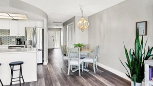 Eine moderne Küche mit weißen Schränken, einem Edelstahlkühlschrank und einer Theke mit Sitzgelegenheiten.