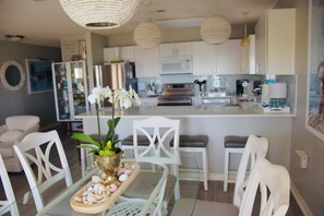 A modern kitchen with white cabinetry, a central island, and pendant lighting. - Grand Caribbean East 301 Destin - Steps to Crystal Beach at Tarpon Beach Park (Destin)