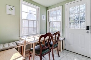 Un comedor con mesa y sillas de madera, un banco a lo largo de la pared, y una puerta blanca con ventana.