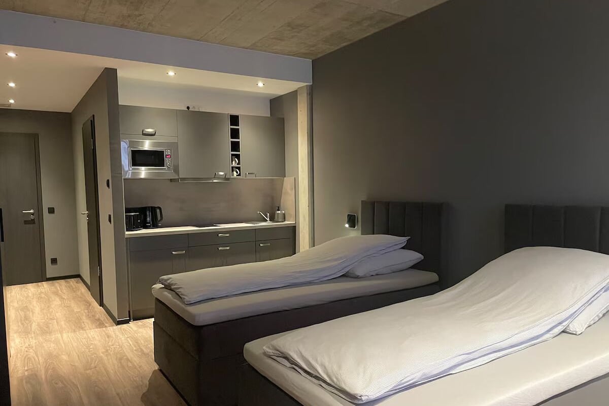 Una camera d'albergo moderna con due letti, angolo cottura e bagno.