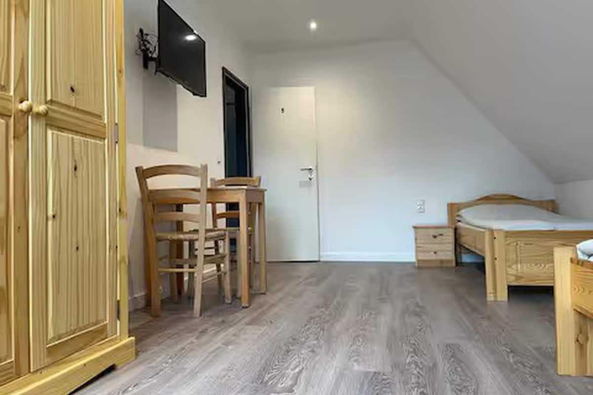 Una camera da letto con un armadio in legno, una scrivania con una sedia, un letto e una televisione montata a parete.