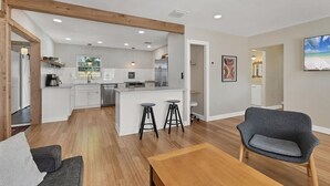 A modern kitchen with white cabinetry, stainless steel appliances, and a central island with stools. - Peaceful Oasis with Pool near Downtown and Beaches (Sarasota)