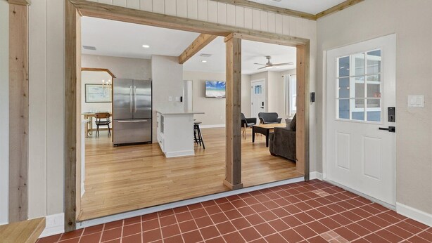 A spacious room with a wooden ceiling, a large sliding door leading to a kitchen area, and a tiled floor. - Peaceful Oasis with Pool near Downtown and Beaches (Sarasota)