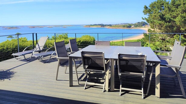 A deck with a table and chairs overlooking a beach and the sea. - Beachfront house in Trébeurden with garden and terrace (Trébeurden)