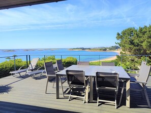 A deck with a table and chairs overlooking a beach and the sea. - Beachfront house in Trébeurden with garden and terrace (Trébeurden)